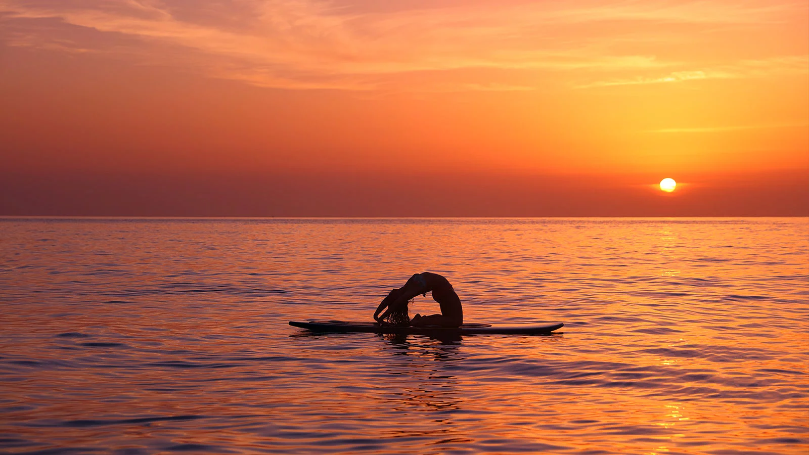 Gün batımında Sup Yoga Yapan Kadın