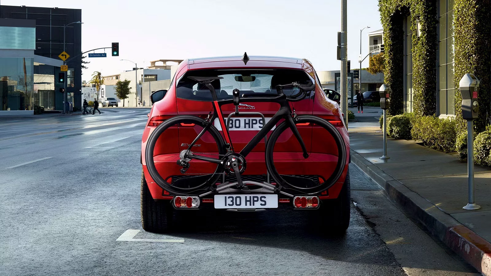 Jaguar E-PACE med hjulmonterede cykelholder parkeret på en byvej.