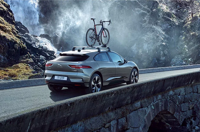 Jaguar I-Pace roof mounted bike rack carrying parked on hill road