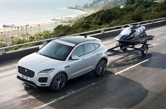 Jaguar E-PACE med jetski parkerad på bro nära strandområde