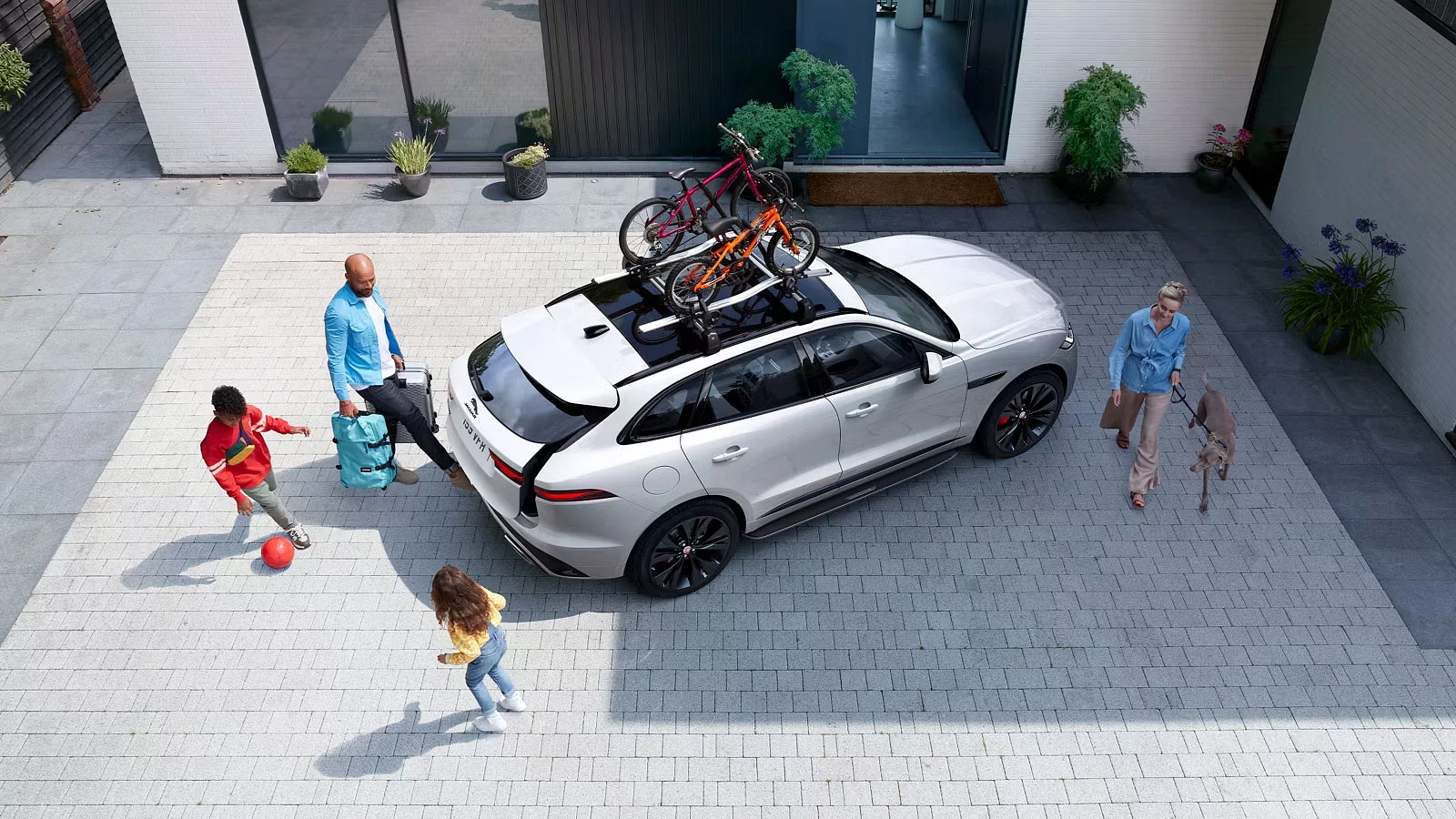 Familie på tur i Jaguar I Pace som er parkeret ved et hus